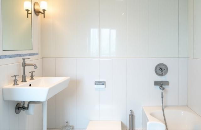 Elegant hotel bathroom featuring white ceramic tiles with subtle blue patterns